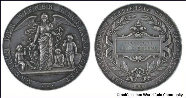 1907 Austria City of Vienna Mercury & Money Medal presented to Prof. Alios Brhuns engraved by J, Schwerdtner. Silver: 62MM./76.3 gm.
Obv: Angels sign with Mercury & Caduceus between putting in industrail goods, behind rail & ship. Rev: In Tablet laurel wreath, engraved dedication in 1907
