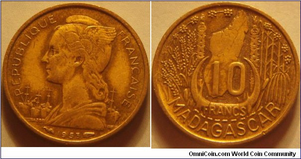 Madagascar | 
10 Francs, 1953 | 
20 mm, 3 gr. | 
Aluminium-bronze | 

Obverse: Female wearing winged Phrygian cap with French flag left, Cargo ships in background, date below | 
Lettering: REPUBLIQUE FRANÇAISE 1953 | 

Reverse: Denomination within horns of a Zebu bull flanked by cluster of sprigs with map of Madagascar, denomination below | 
Lettering: 10 FRANCS MADAGASCAR |
