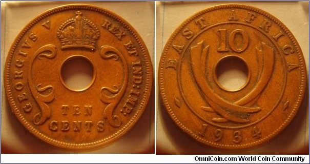 East Africa | 
10 Cents, 1934 | 
31 mm, 11.14 gr. | 
Bronze | 

Obverse: Denomination below centre hole | 
Lettering: GEORGIVS V REX ET IND:IMP: TEN CENTS | 

Reverse: Curved tusks flank the centre hole, numeral denomination above, date below | 
Lettering: EAST AFRICA 10 1934 |