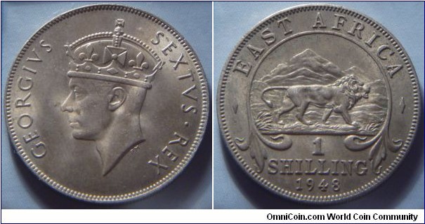 East Africa | 
1 Shilling, 1948 | 
27.8 mm, 7.81 gr. | 
Copper-nickel | 

Obverse: King George VI facing left | 
Lettering: GEORGIVS SEXTVS • REX | 

Reverse: A lion facing right, mountain in background, denomination below, date bottom | 
Lettering: ¬– EAST AFRICA – 1 SHILLING 1948 |