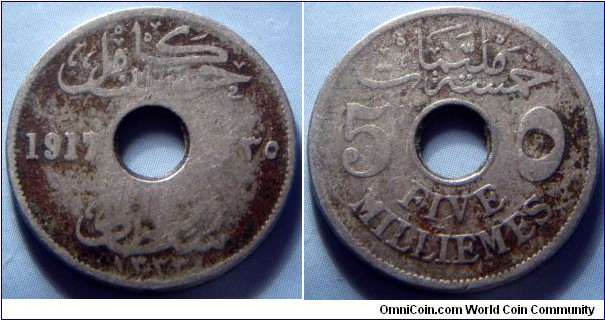 Egypt | 
5 Millièmes, 1917 (1335) | 
23.1 mm, 4.75 gr. | 
Copper-nickel | 

Obverse: Hussein Kamel, Sultan of Egypt written in Arabic, date divide by centre hole | 
Lettering: حسين كامل 1917 ١٣٣٥ سلطان مصر ۱۳۳۳ | 

Reverse: Denomination written in Arabic above, numbers divided by centre hole, written in English below | 
Lettering: خمسة مليمات 5 ٥ FIVE MILLIEMES |