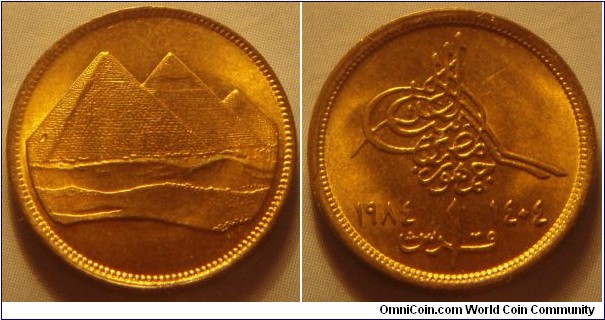 Egypt | 
1 Piastre, 1984 (1404) | 
18 mm, 2 gr. | 
Aluminium-bronze | 

Obverse: The three pyramids of Giza | 

Reverse: Denomination, Gregorian date right, Arabic date left | 
Lettering: جمهورية مصر ١ قرش ١٤٠٤ ١٩٨٤ |