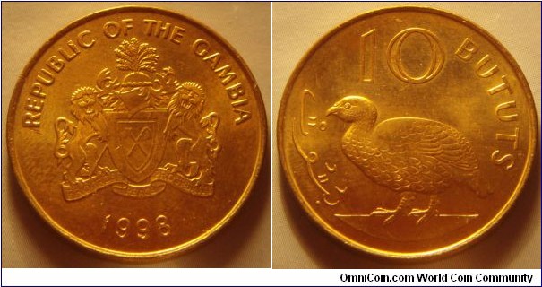 The Gambia | 
10 Bututs, 1998 | 
26 mm, 5.6 gr. | 
Brass plated Steel | 

Obverse: National Coat of Arms, date below | 
Lettering: REPUBLIC OF THE GAMBIA 1998 | 

Reverse: Double-spurred francolin | 
Lettering: بتوت 10 BUTUTS |