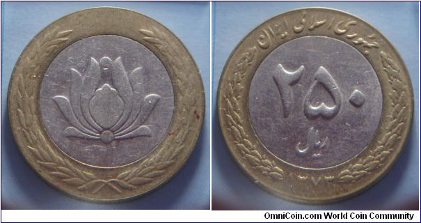 Iran | 
250 Rials, 1994 (1373) | 
28.3 mm, 10.6 gr. | 
Bi-metallic: Copper-nickel centre in Brass ring | 

Obverse: Grenadine blossom within wreath | 

Reverse: Denomination, date below | 
Lettering: جمهوری اسلامی ايران ۲۵۰ ريال ۱۳۷۳ |