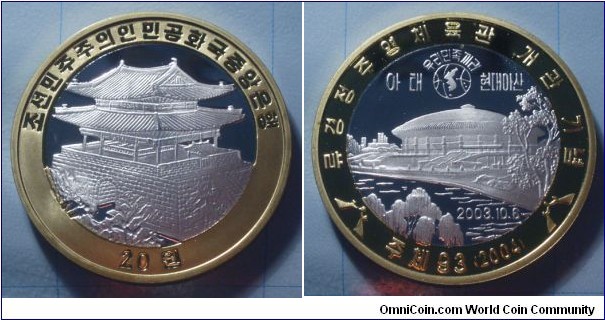 North Korea | 
20 Won, 2004 – Peace Meeting | 
40.33 mm, 15.3 gr. | 
Bi-Metallic: Aluminium centre in Brass ring | 

Obverse: Great East Gate, denomination below | 
Lettering: 조선민주주의인민공화국중앙은행20 원 | 

Reverse: Map of the Korean peninsula, Pyongyang Arena with dates of the grand opening, date below | 
Lettering: 류경정주영체육관 개관 기념 주체93 (2004) 우리민족끼리 이태 현대아산 |