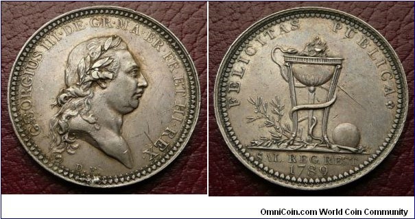 1789 UK George III Medal by Droz. Silver: 34MM.
Obv: Bust of King George III to right., legend GEORGIUS III DE GR MA BR FR ET HI REX, initials D.F. (for Droz) below. Rev: Serpent entwining around an Urn, with Greenery & Orb, legend FELICITAS PUBLICA, exergue SAL.REG.REST.1789.
