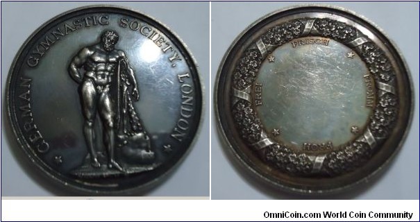 1800 o j UK German Gymnastic Society London Wresting Medal by Waterlows Limited SC/O.K.FFC.  Silver: 51MM./64 gm.
Obv: Hercules resting with his mace on the stone. Legend GERMAN GYMNASTIC SOCIETY, LONDON. Signed WATERLOWS LIMITED SC,O.K.FFC. Rev: Wreath with ribbons surrounding on outer edge. Legend FREI FRISCH FROMM FROH seperated with Stars. Blank centre.
