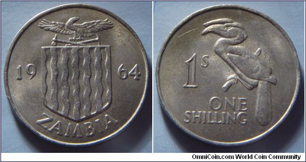 Zambia | 
1 Shilling, 1964 | 
23.6 mm, 5.6 gr. | 
Copper-nickel | 

Obverse: National Coat of Arms separates date | 
Lettering: 1964 ZAMBIA | 

Obverse: Crowned Hornbill, denomination below | 
Lettering: 1s ONE SHILLING |