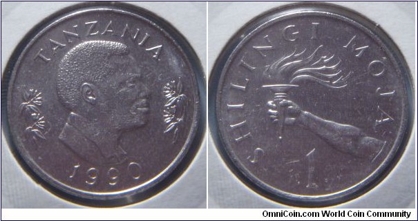 Tanzania | 
1 Shilling, 1990 | 
23.5 mm, 6.5 gr. | 
Nickel clad Steel | 

Obverse: Second president, Ali Hassan Mwinyi, facing right flanked by flowers, date below | 
Lettering: TANZANIA 1990 | 

Reverse: Hand holding a torch, denomination below | 
Lettering: SHILINGI MOJA 1 |