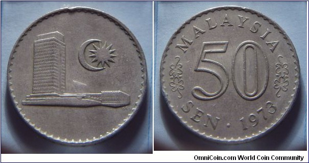 Malaysia | 
50 Sen, 1973 | 
27.8 mm, 9.4 gr. | 
Copper-nickel | 

Obverse: Parliament building, moon crescent and a 13-pointed star right | 

Reverse: Denomination, date below | 
Lettering: MALAYSIA 50 SEN • 1973 |