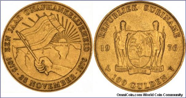 The 1976 issue commemorates the first anniversary of independence.
The obverse bears the Suriname coat of arms, with the inscription
REPUBLIEK SURINAME
1976
100 GULDEN
The reverse shows the flag of Surinam superimposed on a map of Surinam and the rising sun. The legend reads:
EEN JAAR ONAFHANKELIJHEID
1975 - 25 NOVEMBER - 1976.