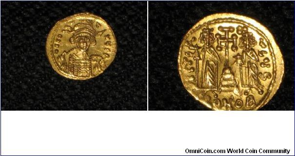 This is a gold coin from the Byzantine Empire (Constantine IV).  The Obverse has a picture of the Emperor with a helmet on holding a spear and the reverse shows 2 brothers to the Emperor on either side of the cross.  My grandpa gave me this coin, it's as if it has never been touched.