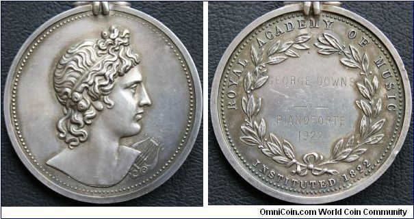 Silver Medal 41mm: Obverse: Bust of Apollo, head facing right; a lyre beneath the right shoulder Rev: ROYAL ACADEMY OF MUSIC.  INSTITUTED 1822.  GEORGE DOWNS PIANOFORTE. 1922. With suspension loop attached to a small claw. By Benjamin Wyon, struck by John Pinches