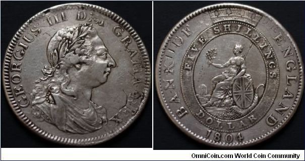 GEORGE III
Emergency Issue Dollar. (Current for 5s. Until 1811, revalued at 5s. 6d. Withdrawn from circulation in 1817) Obverse: laur. And dr. bust of king. Reverse: Brittania seated l. Re-struck from Spanish-American 8-Reales until 1811. This coin  shows some faint features of the original host coin such as the IIII of Carlos the IV